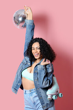 Happy woman with disco ball and roller skates on pink background