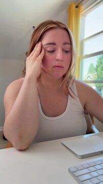person sits at the computer, scrolls trackpad, types, and looks hesitant or uncertain
