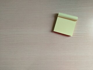 Blank Yellow Sticky Note Pad Placed on Wooden Desk Surface with Copy Space © Putu