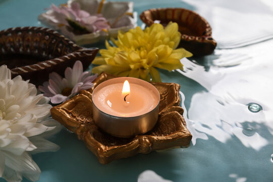 Diya lamps with beautiful flowers and burning candle in water on blue background. Divaly celebration