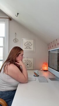 tired, overworked, stressed woman is in front of a desktop computer, scrolling, puts face in hands, bites nails