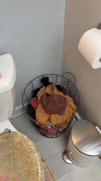 woman holds up a pair of underwear and throws it into the dirty laundry basket - POV shot