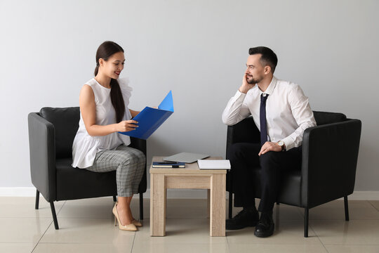 Human resources manager interviewing applicant near light wall in office