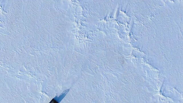 Hovercraft moving across frozen Lake Baikal surface. Amphibious vehicle traveling snowy white ice. Expedition transport winter landscape. Extreme travel exploration cold Russia. Aerial drone top view.