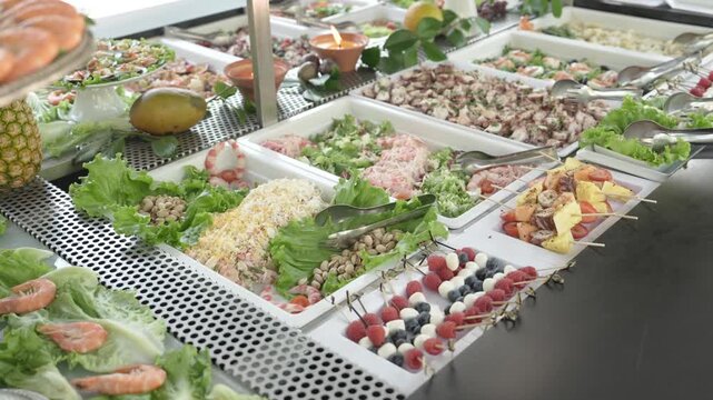 Chilled buffet counter lined with shrimp lettuce salads berry skewers and cold starters at a wedding catering service.