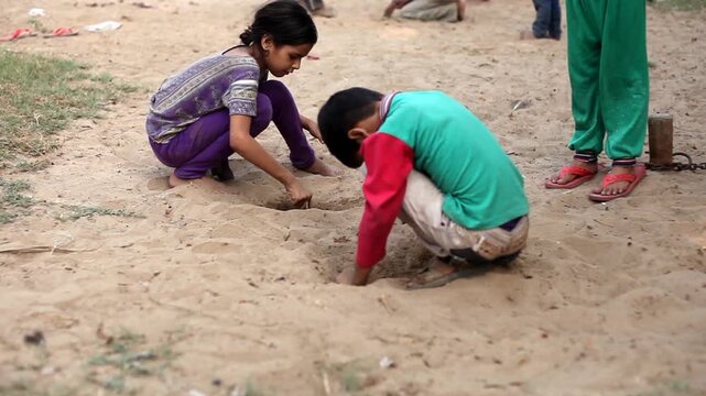 Group of children playing with marble balls outdoor in nature during summer season.