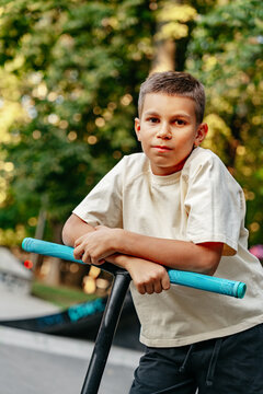 Boy resting on scooter at a park during the afternoon on a sunny day