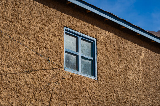 Blue square wooden window on adobe wall in northern Chile