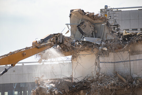 Construction site, demolition of reinforced concrete structure, gutting and renovation, hydraulic hammer dismantles building, caterpillar excavator machine