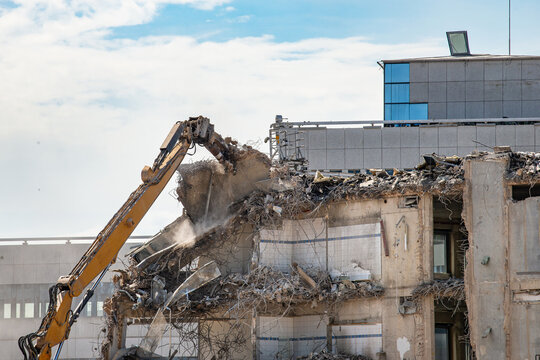 Construction site, demolition of reinforced concrete structure, gutting and renovation, hydraulic hammer dismantles building, caterpillar excavator machine