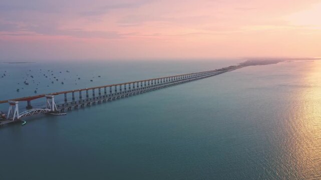 Aerial drone view of the Pamban railway bridge and parallel road bridge stretching across the turquoise waters of the Palk Strait near Rameswaram, Tamil Nadu, India.