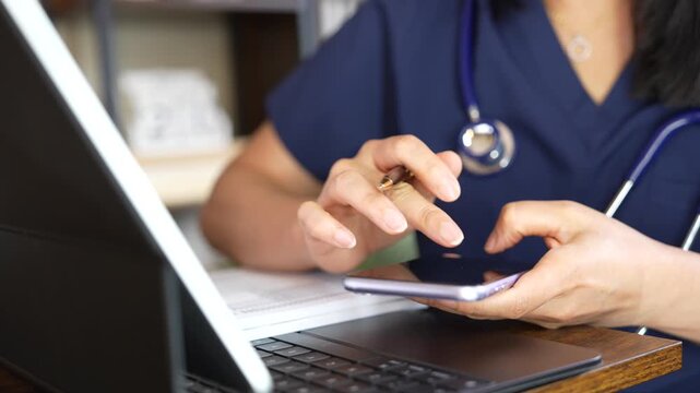 Healthcare professional reviews patient records, checks medical information on a smartphone, enters clinical data on a laptop, and writes notes for medication and pharmacy documentation.