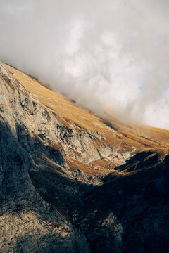 Clouds drift over a sunlit golden mountain slope