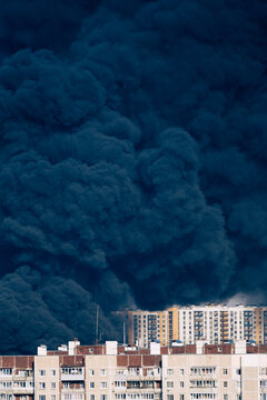 Thick black smoke rising over urban buildings
