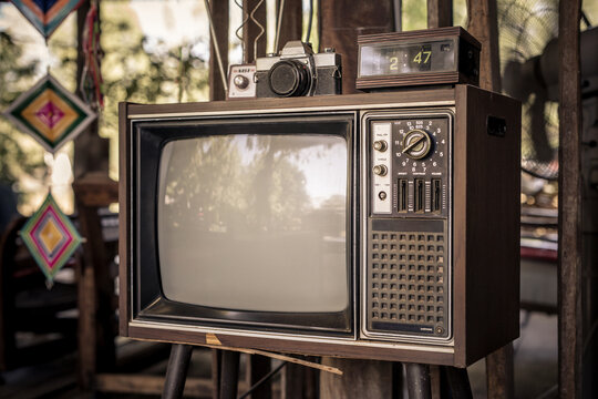 Retro old television set with an antenna no longer usable, vintage look with old camera at home.