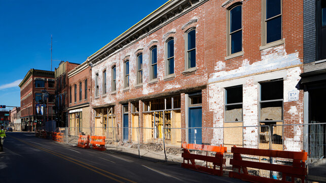 professional documentary architectural photography of a generic older commercial building undergoing renovation, original brick exterior partially restored beside a newly finished section, 
