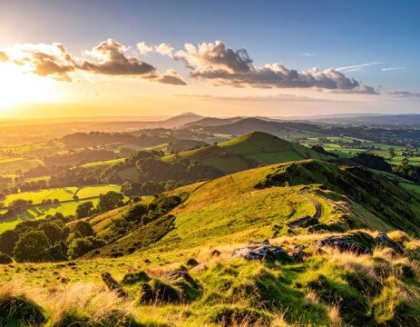 Golden hour illuminates rolling green hills and a winding path under a cloudy sky.
