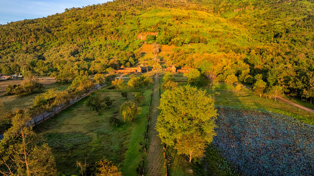 Aerial drone view of Wat Phou, Laos, featuring traditional Lao dancers, Buddhist monks visiting the ancient temple, and locals offering food during a cultural and religious ceremony.