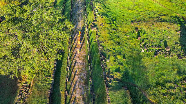 Aerial drone view of Wat Phou, Laos, featuring traditional Lao dancers, Buddhist monks visiting the ancient temple, and locals offering food during a cultural and religious ceremony.
