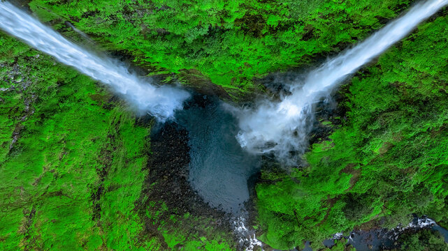 Aerial view of Tad Fane Waterfall in Laos, with a tourist enjoying tea while suspended on a zipline above the spectacular twin cascades and lush rainforest of the Bolaven Plateau.
