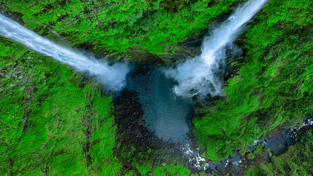 Aerial view of Tad Fane Waterfall in Laos, with a tourist enjoying tea while suspended on a zipline above the spectacular twin cascades and lush rainforest of the Bolaven Plateau.
