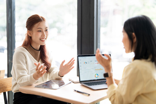 Asian Business Women Smiling and Gesturing During Project Discussion