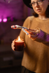 realistic witch holding voodoo doll and candle casts spell. Everyday life intertwined with traditional witchcraft, magic and mystical atmosphere. © Andrii Lysenko