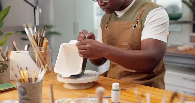 Pottery, hands and man painting ceramic in shop for merchandise, creative and small business. Black person, workshop and handmade craft store for manufacturing, productivity or artist process