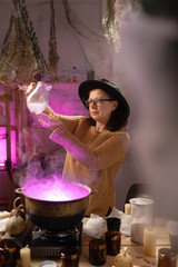 realistic witch brewing potion in cauldron. Everyday life intertwined with traditional witchcraft, magic and mystical atmosphere. © Andrii Lysenko