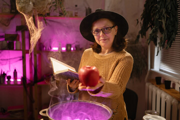 realistic witch over cauldron brewing potion casting spells put poisoned apple. Everyday life intertwined with traditional witchcraft, magic and mystical atmosphere. © Andrii Lysenko