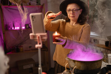 realistic witch vlogger reviewing brewing potion in cauldron, broadcasting on social media. Everyday life intertwined with traditional witchcraft, magic and mystical atmosphere. © Andrii Lysenko