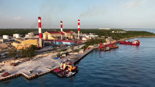 Nassau, New Providence, The Bahamas - 14 September 2026: Aerial view of Clifton Bay Power Plant with industrial smokestacks and tugboats docked at the pier along the coastline.