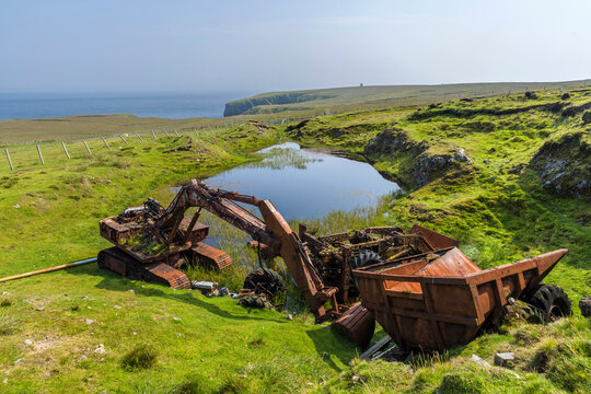 Rusty abandoned construction machinery by pond