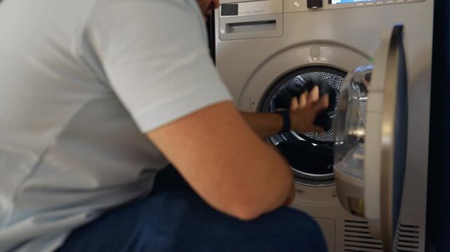 Man repairs washing machine in home laundry space