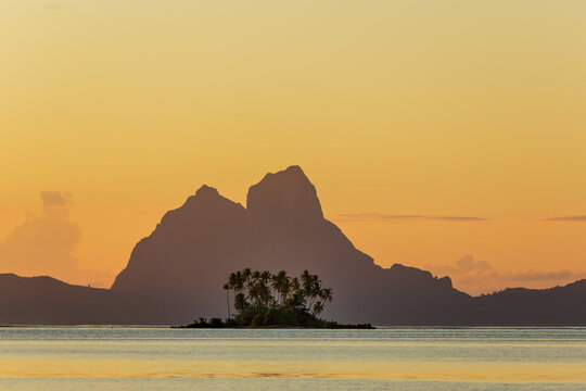 FRENCH POLYNESIA. TAHAA ISLAND. MOTU ON THE CORAL BARRIER. IN THE BACKGROUND, THE ISLAND OF BORA BORA