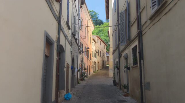 vicolo stretto e silenzioso in un antico borgo medievale italiano. Edifici storici con facciate color pastello sotto la luce del sole