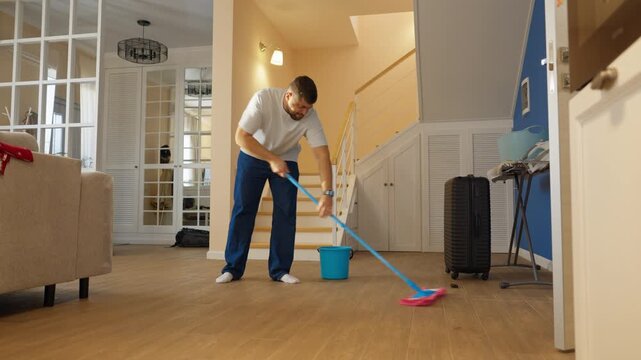 Man mops the floor in a modern living room during the day