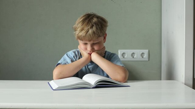 A 6&ndash;7-year-old boy reads a book at home while supporting his head with both hands. The video illustrates an incorrect reading posture, fatigue, prolonged sitting, poor study habits, ergonomics, and th