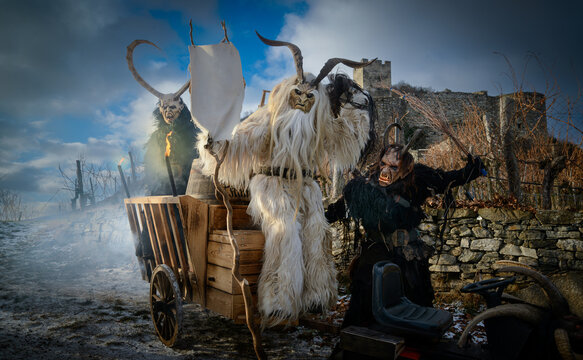Traditional Austrian Krampus and Perchten figures with wooden masks and rustic cart at Hinterhaus castle ruin in Wachau