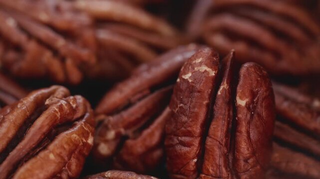 Extreme macro shot of fresh premium pecan nuts filling the frame with selective focus, rotating slowly with artistic lighting. Perfect for healthy eating, gourmet food, culinary, and dietary content.