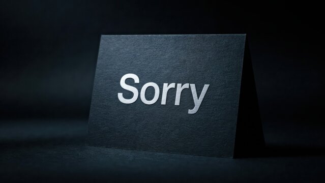 A black greeting card with the word Sorry printed in silver on a dark background. This minimalist card is perfect for expressions of apology or regret.