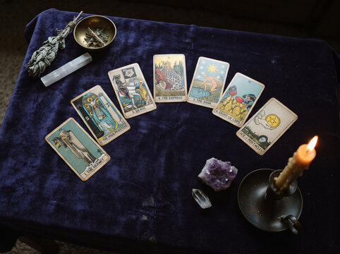 Tarot card reading spread on dark blue velvet table with crystals, sage, and burning candle