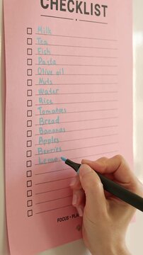 Woman hand checking grocery checklist with blue marker close up video.