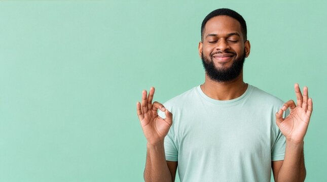 Peaceful Black man meditating with eyes closed on green background