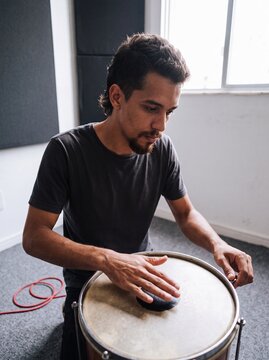 Young percussionist playing a surdo drum in a rehearsal studio
