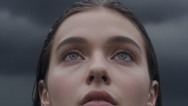 Young Woman Gazing Upward Against Dark Ominous Sky Background