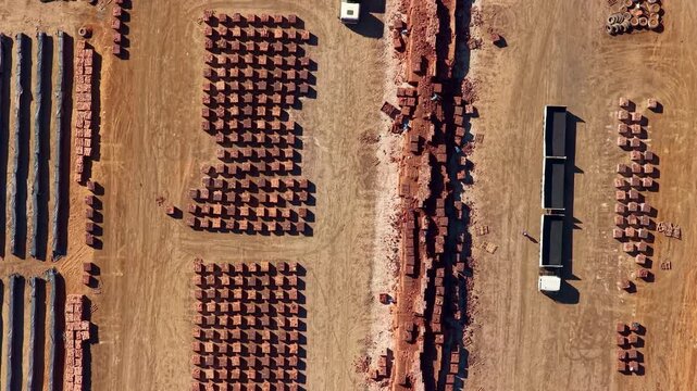 Top down aerial. Factory workers hand sorting clay building bricks at brickworks