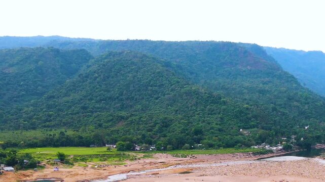 Border hill with dry riverbed and aboriginal settlement at Sylhet, Bangladesh india border region - aerial panning shot.
