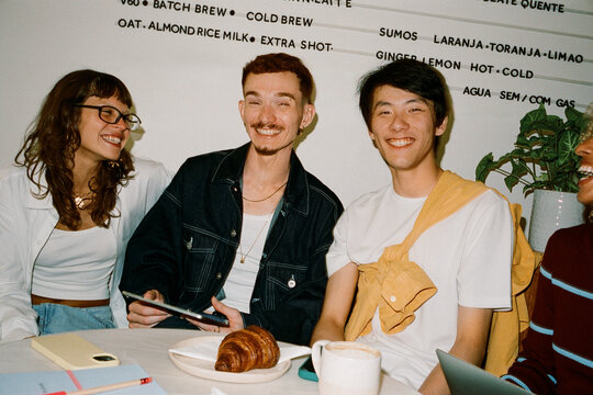 Young entrepreneurs laughing over coffee and planning a project