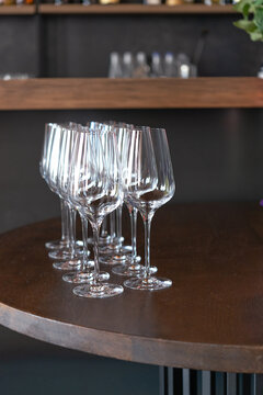 Elegant crystal wine glasses arranged on a wooden bar table in a sophisticated restaurant, sparkling glassware reflecting light, luxury dining atmosphere, refined hospitality and celebration concept